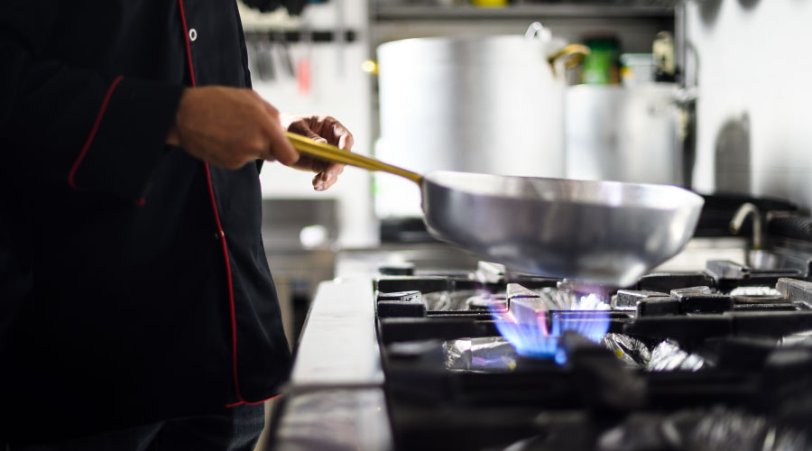 cocinero profesional que cocina sabiendo cómo reducir el consumo energético en cocinas profesionales